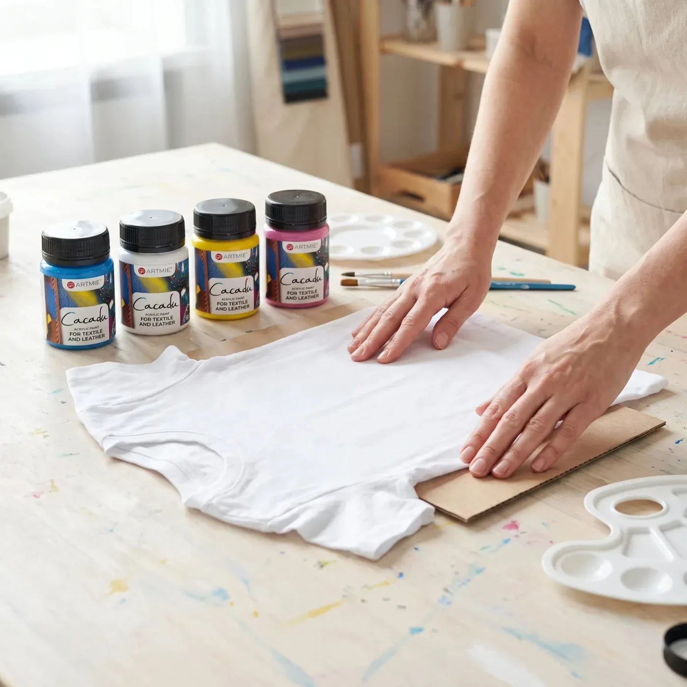Lisciatura di una t-shirt bianca con cartoncino all'interno, accanto i colori Cacadu per tessuto
