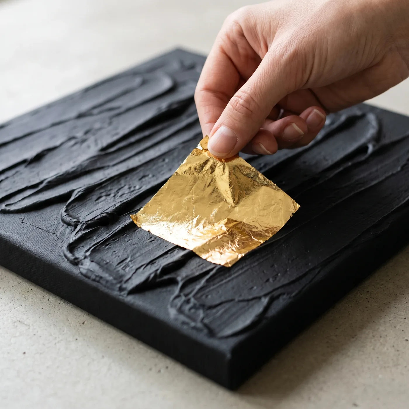 Posa di un foglio di foglia d'oro sul rilievo nero materico